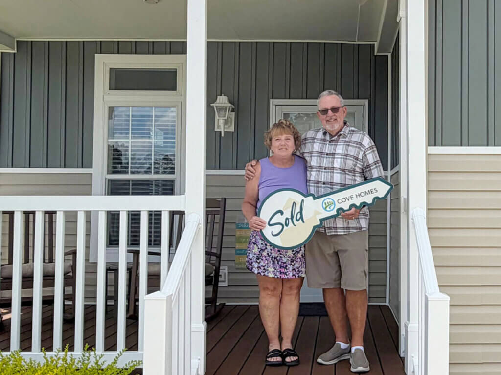 New homebuyers holding a ceremonial key in front of their home at Rolling Greens Village in Ocala, Florida.