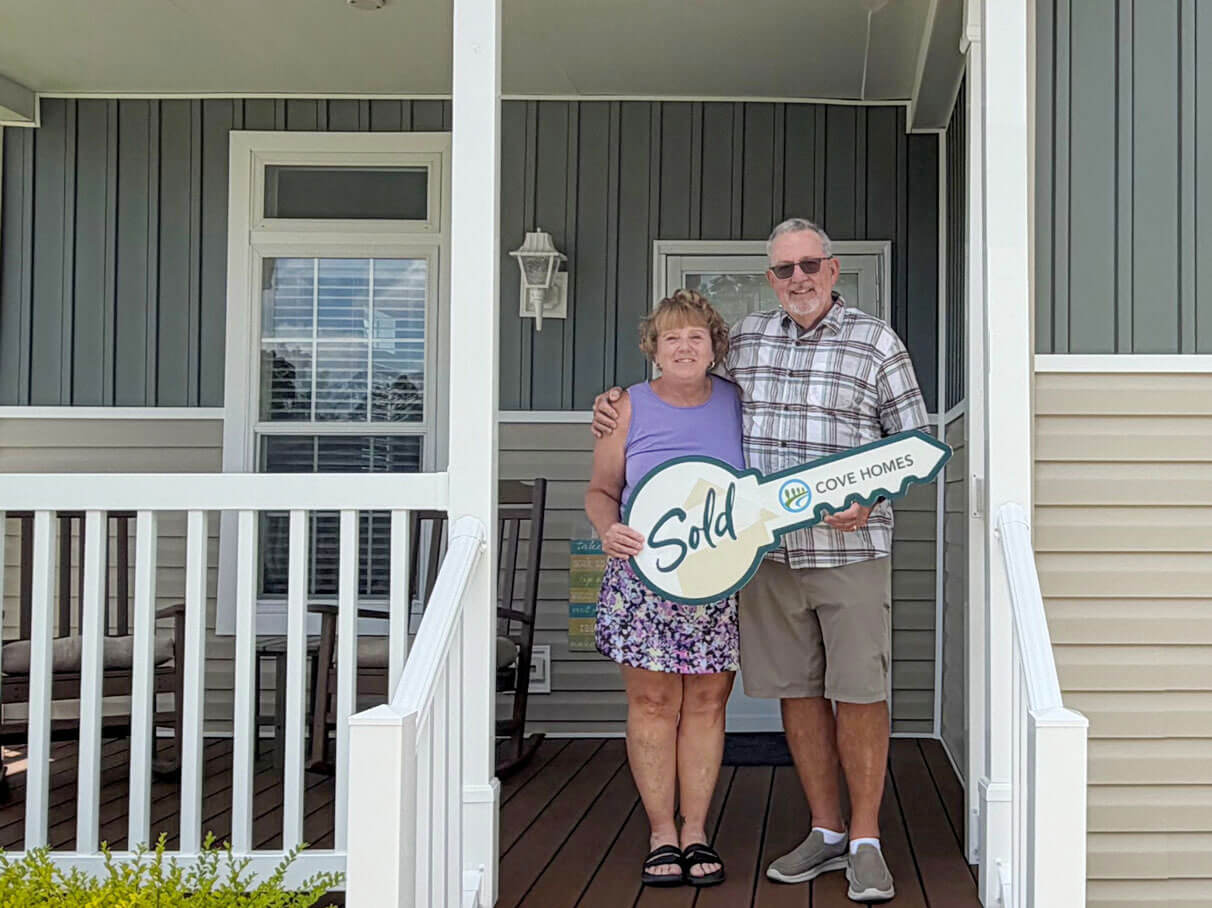 New homebuyers holding a ceremonial key in front of their home at Rolling Greens Village in Ocala, Florida.