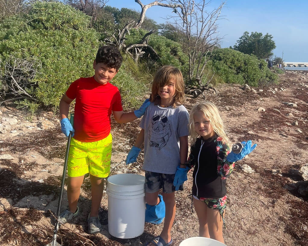 Three kids cleaning up the beach along Big Pine Key RV Park in Florida.