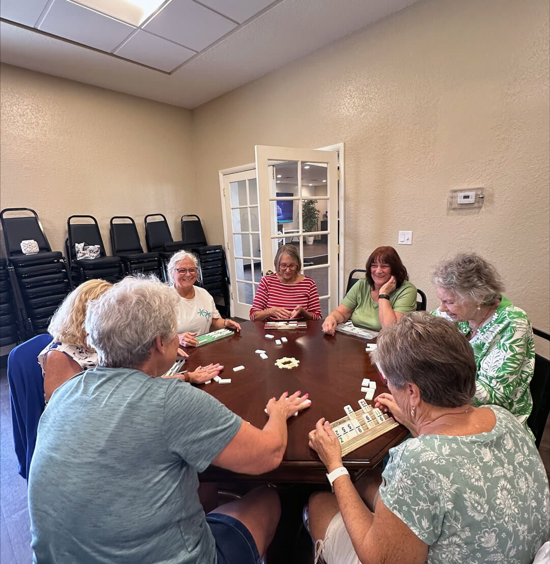 guests gathered around a table in the clubhouse playing dominoes