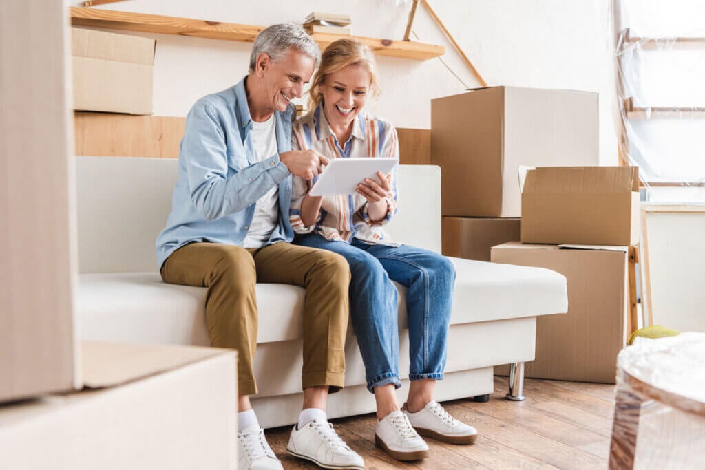 New homebuyers looking at a tablet while surrounded by moving boxes