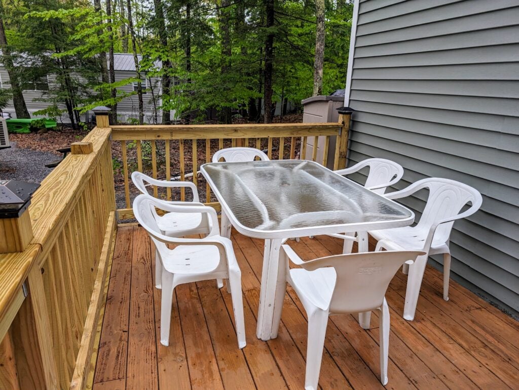 table with glass top with chairs around on a deck