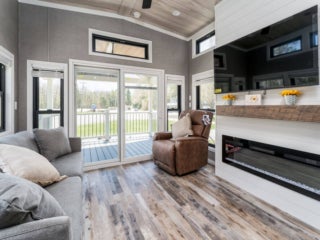 Living room, fireplace, and TV inside the model cottage at Point Sebago. The photo shows an park model created by Elevation.