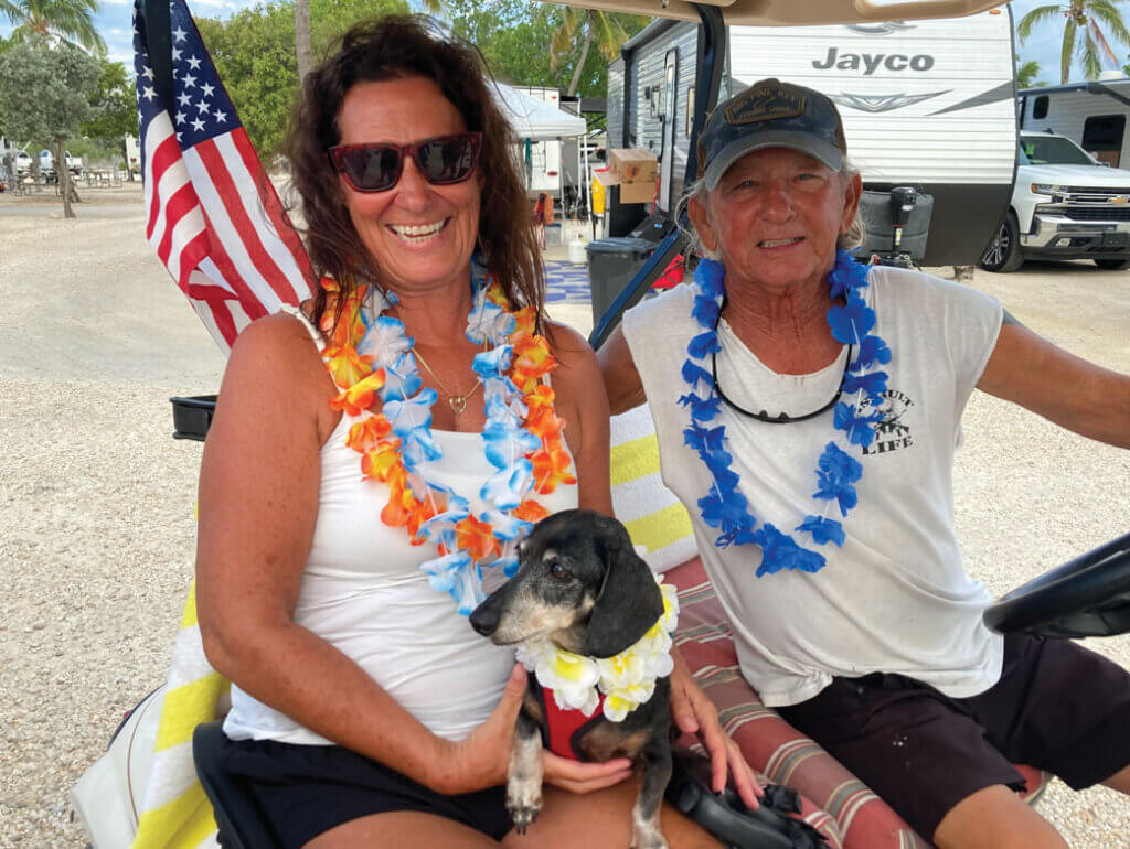 Couple posing with their dog in a golf cart at Big Pine Key RV Park in Florida.