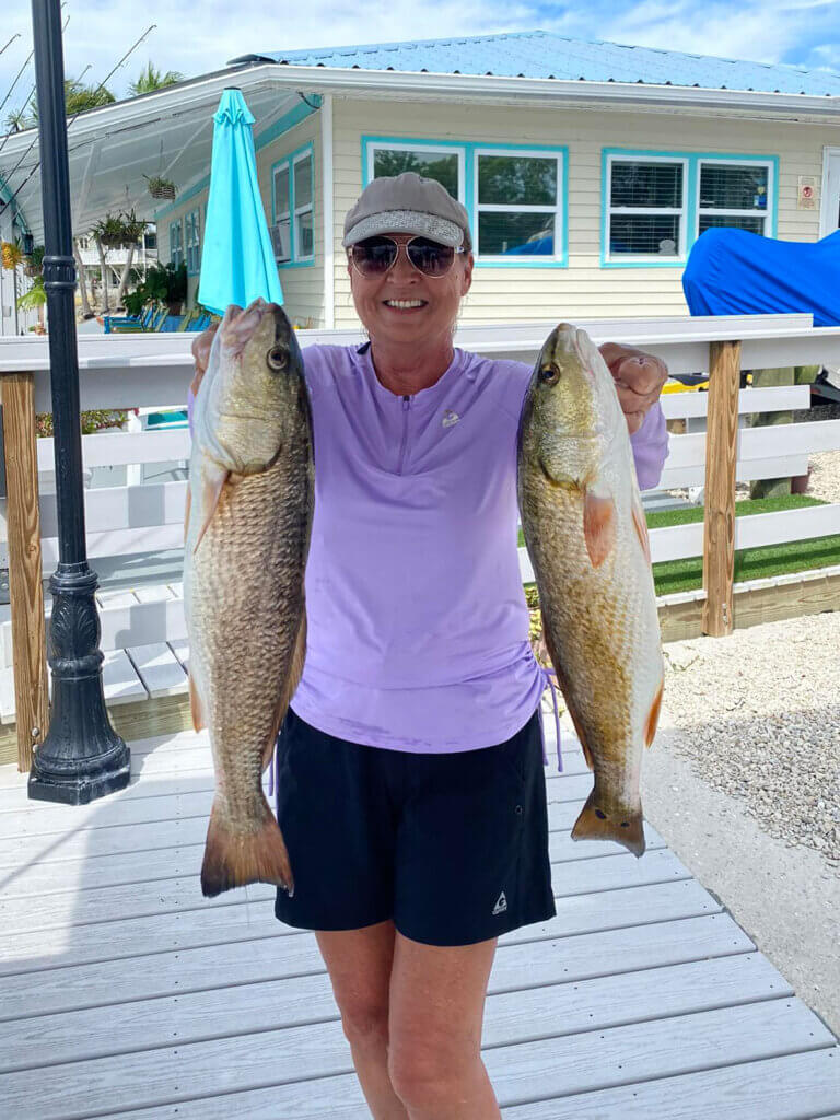 Woman shows off two redfish she caught while fishing near Chokoloskee RV Park in Florida.