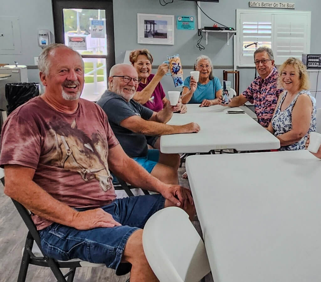 Guests at Holiday RV Park in Leesburg, FL hold up their coffee cups as they gather around for lifestyle event.