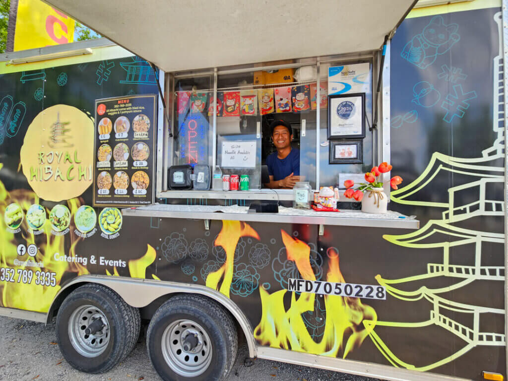 Man inside Royal Hibachi Food truck parked at Holiday RV Park in 55+ Leesburg community.
