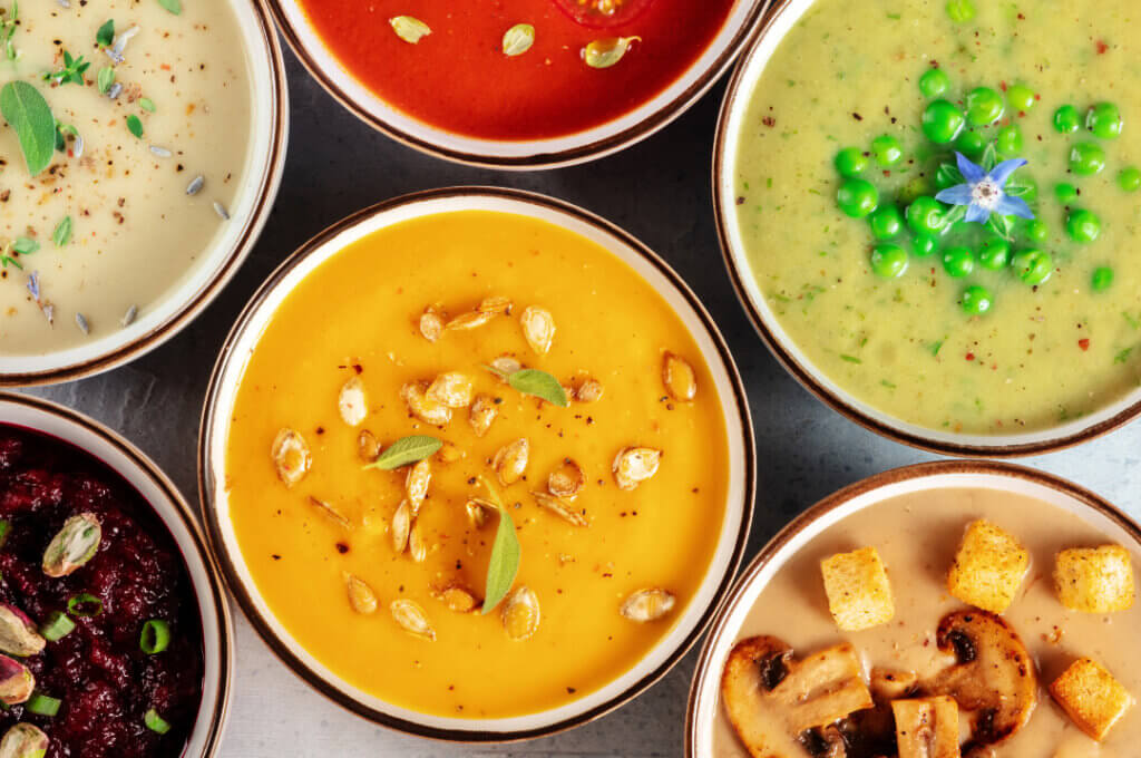 Six different types of soup bowls lined up for soup sampling.