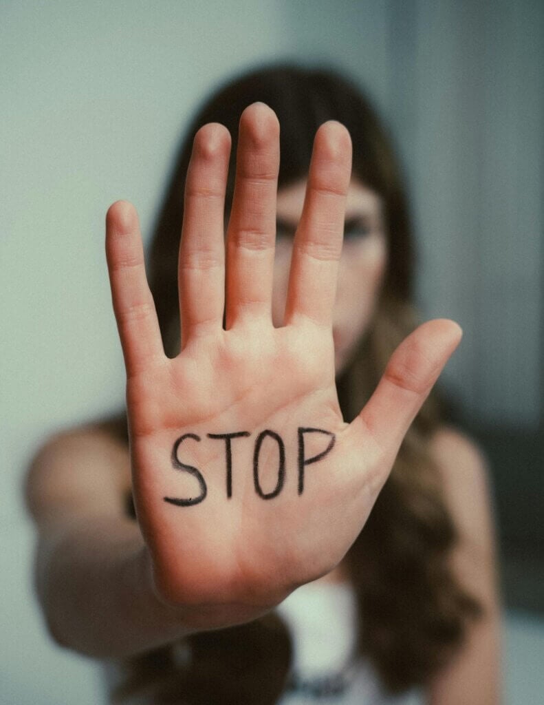 Girl holding out hand with STOP written on it.