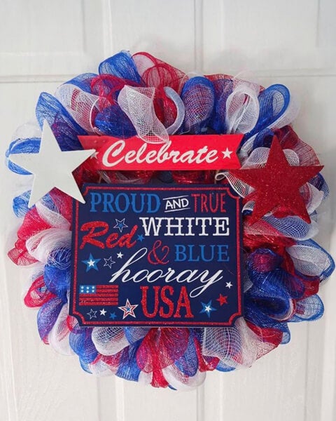 A patriotic wreath crafted by residents at The Meadows in Tarpon Springs featuring red, white, and blue mesh, decorative stars, and a festive sign that reads “Proud and True Red White & Blue Hooray USA.