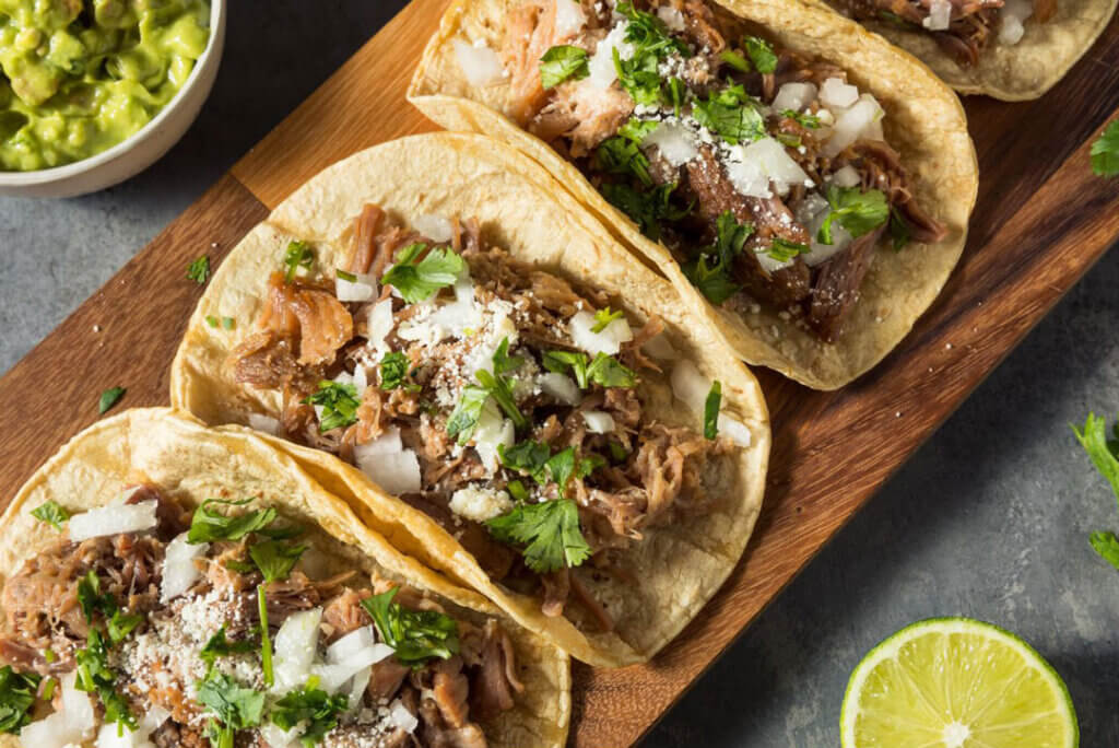 Tacos lined up on a board.