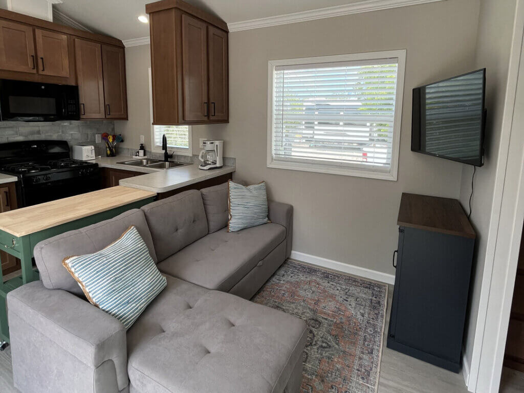 Couch, TV, and kitchen inside of a vacation rental at Big Pine Key RV Park in Florida.