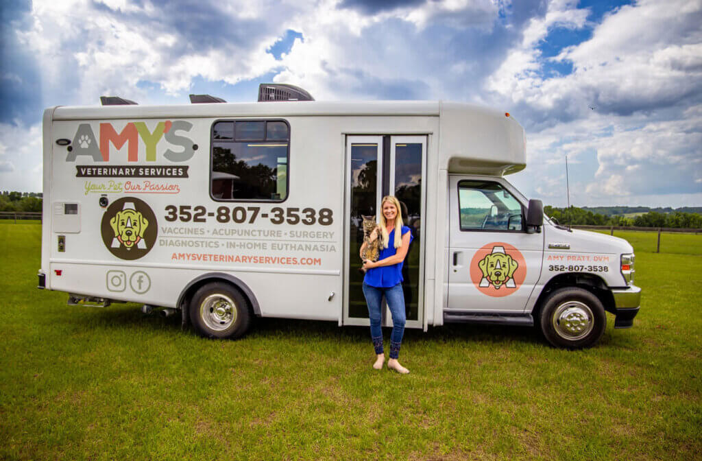 Dr. Amy standing outside of her mobile Veterinary Truck in Florida while holding a cat.