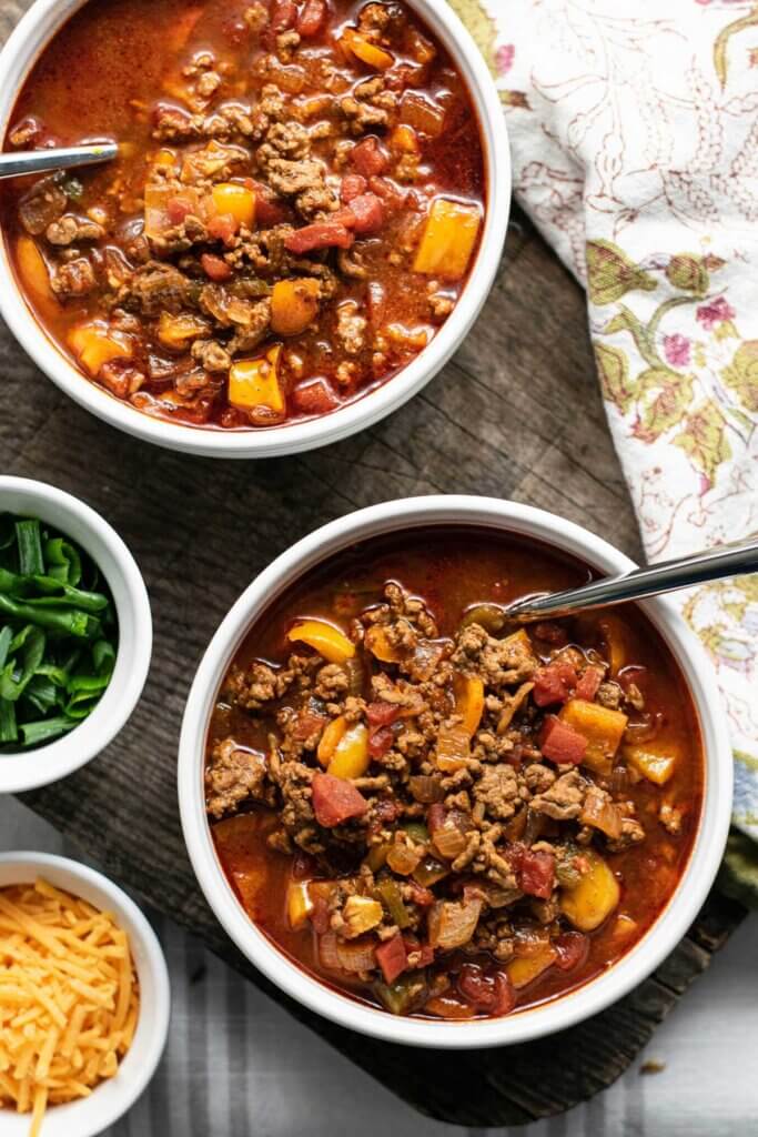 Bowls of chili with cheese and green onion toppings on the side