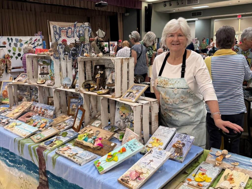 A woman standing next to her craft fair booth at Cypress Lakes Village in Lakeland, Florida.