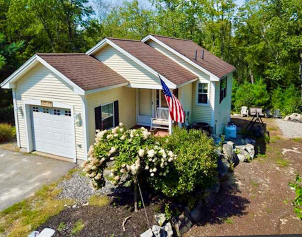 Exterior of home with American flag and bush