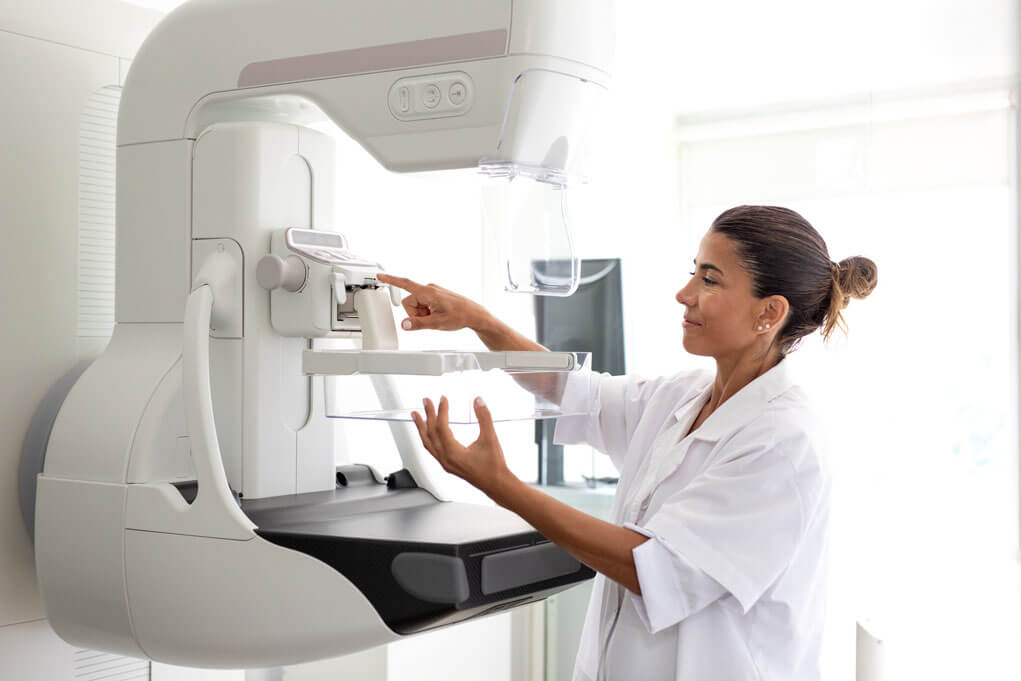 Female medical imaging technician prepare and operates a state-of-the-art mammography machine.