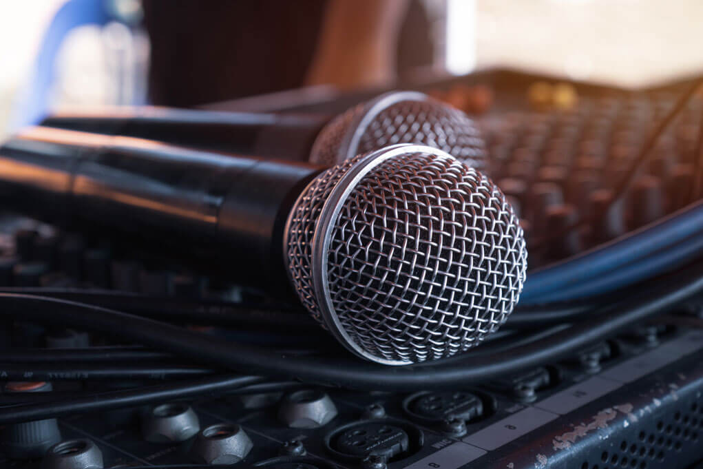 Two microphones sitting on a soundboard.
