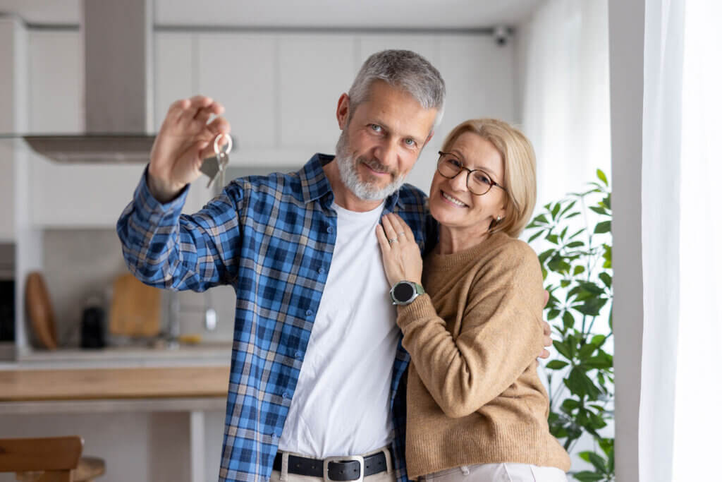 This image depicts a happy couple proudly holding their keys in a stylish kitchen, capturing their milestone moment together.