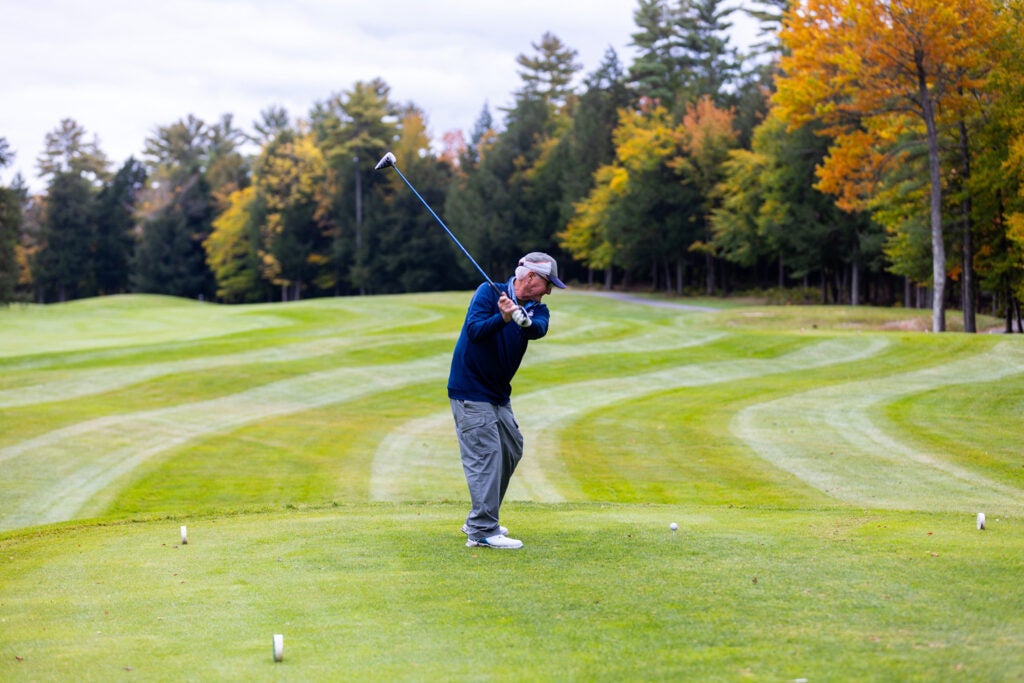 Man teeing off in the fall