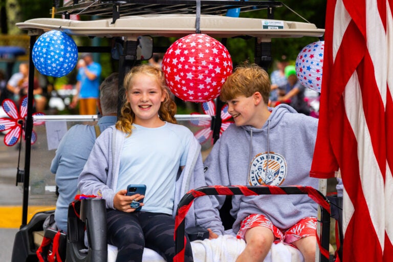 two kids on back of decorated golf cart