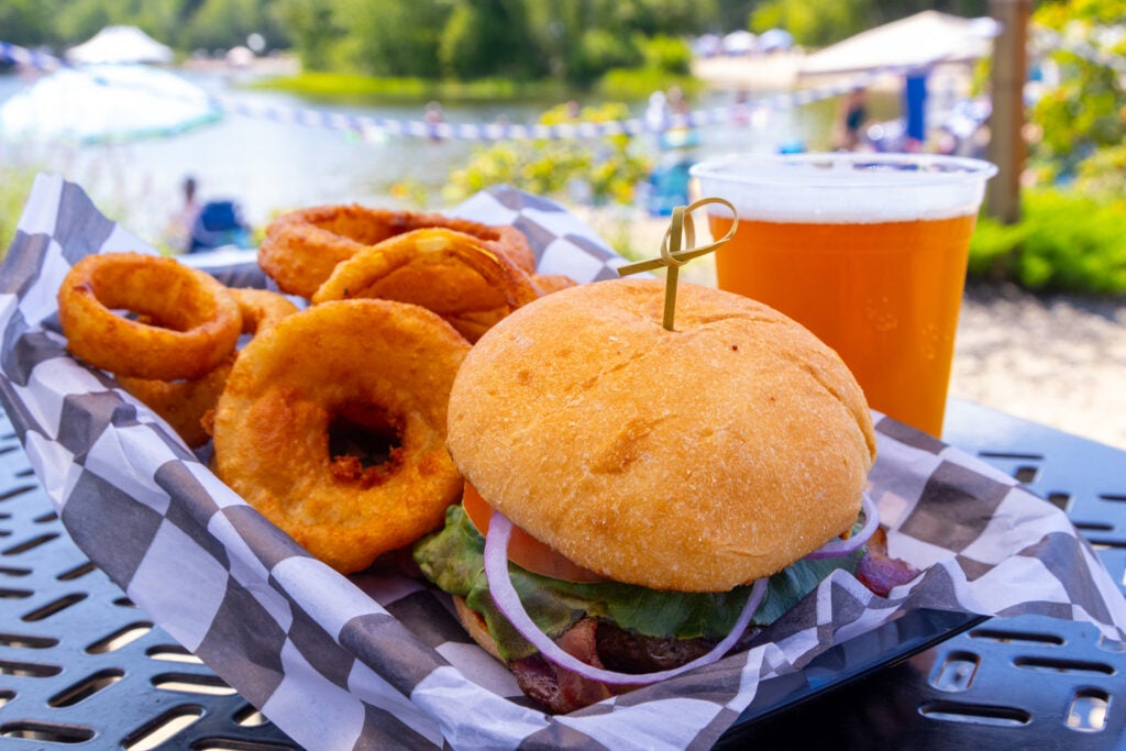 Cheeseburger with onion rings and draft beer on table