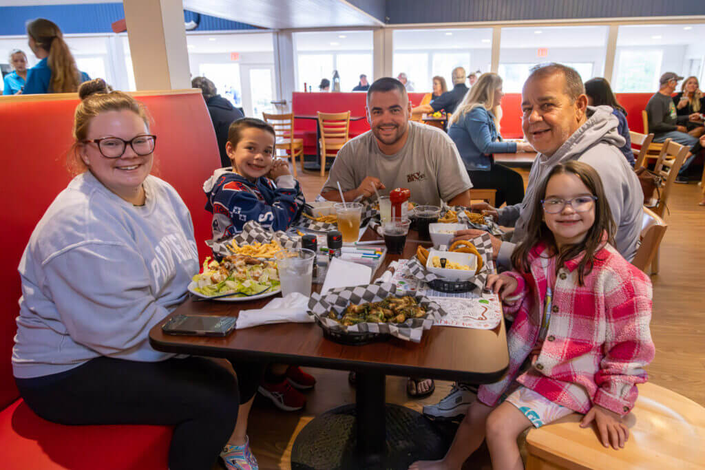 Family of five eating a meal in restaurant.