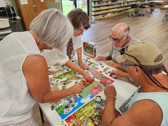 Residents work together to finish a puzzle during the summer series of events called Adult Twisted Summer Camp at Holiday RV Park in Leesburg, Florida.
