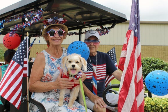 Residents dressed up in red white and blue in decorated golf carts for a 4th of July golf cart parade through Rolling Greens Village in Ocala, FL.