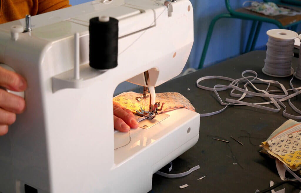 Close-up of a seamstress's hands illuminated by her sewing machine during her sewing work