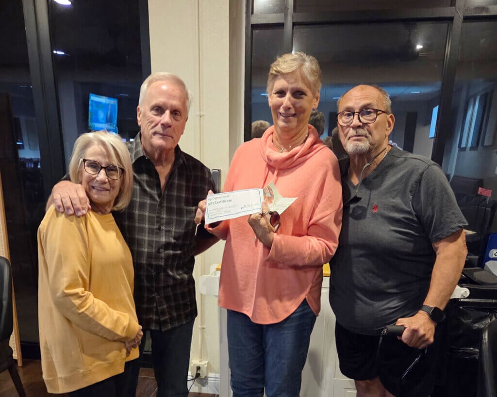 Two couples holding a Big Cypress Grill gift certificate after winning trivia night in Lakeland, Florida.