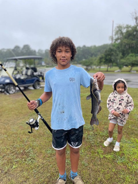 13 year old boy holding fish and fishing pole