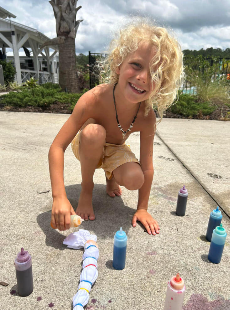 little boy on sidewalk tie dying a tshirt