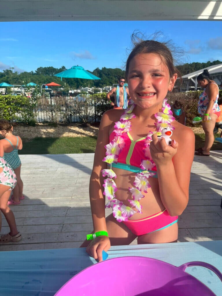 Guest at CreekFire RV Resort wearing a lei surrounded by other kids playing at a luau themed weekend at the Park.