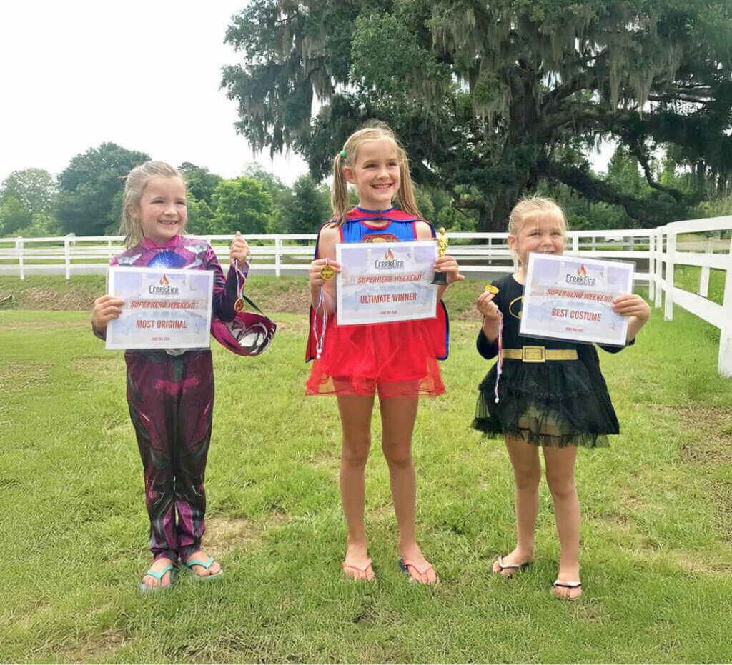 Girls in superhero costumes with awards from themed weekends at CreekFire RV Resort in Savannah.