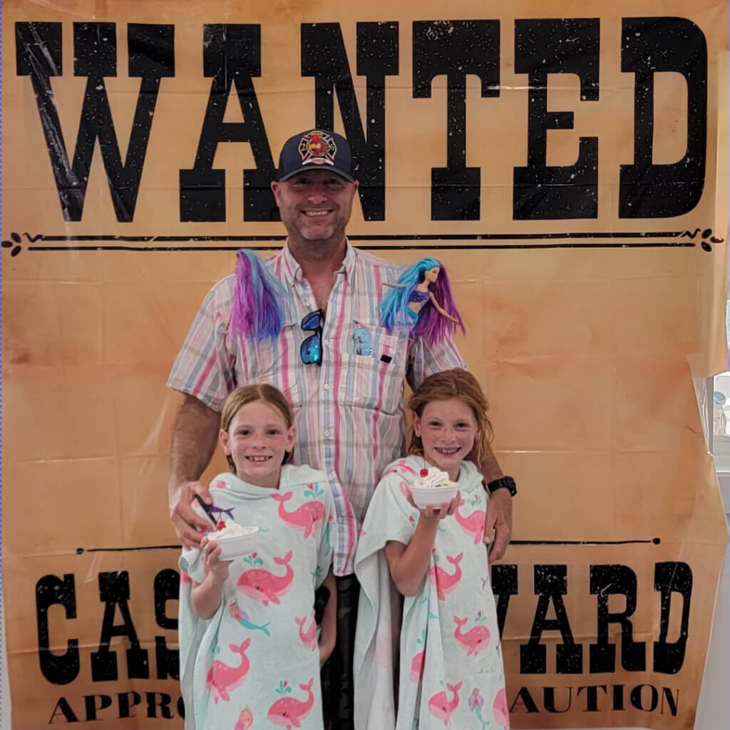 Father and two daughters holding ice cream treat from Wild West Wanted Sign during themed weekends.