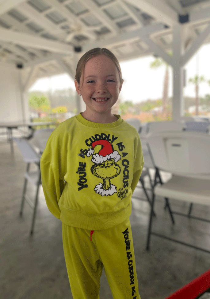 little girl smiling in grinch sweat suit