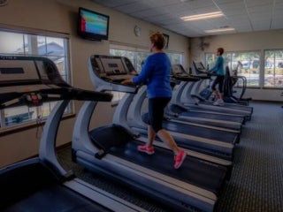 two senior ladies in the fitness center using the elliptical machine and treadmill