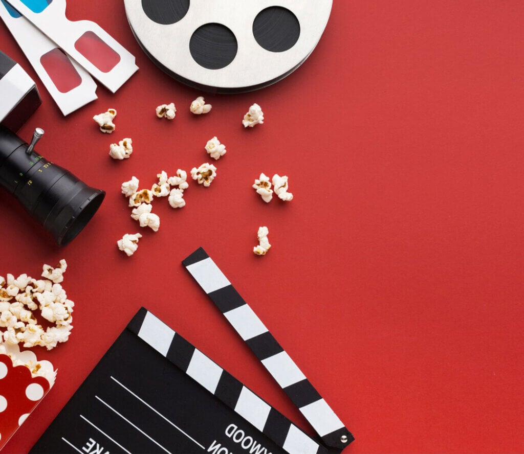Stock photo movie reel, popcorn, camera on red background.