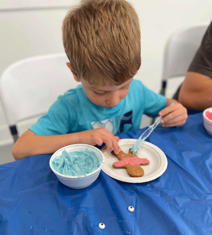 boy decorating gingerbread man cookie with frosting