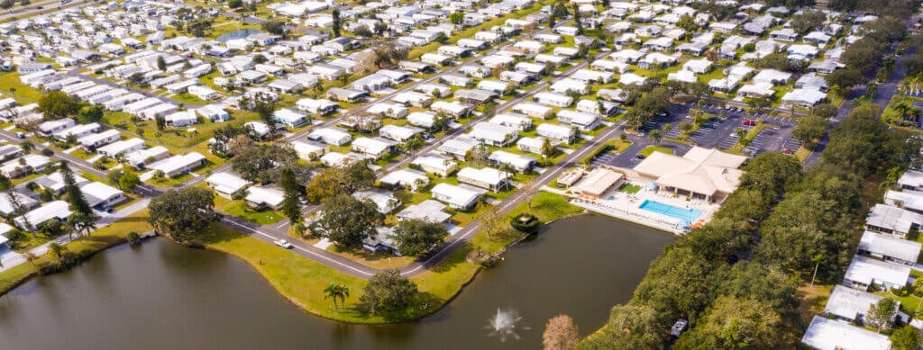 Overhead view of Camelot Lakes Village&#039;s pond and manufactured homes.