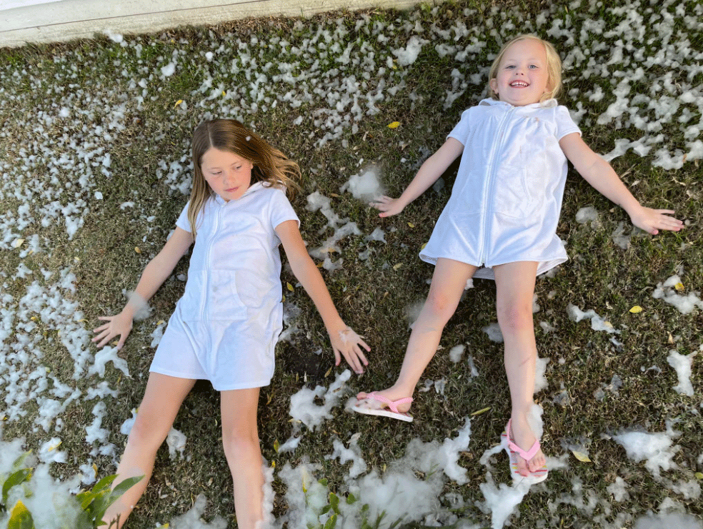 girls laying on the ground making snow angels in fake snow