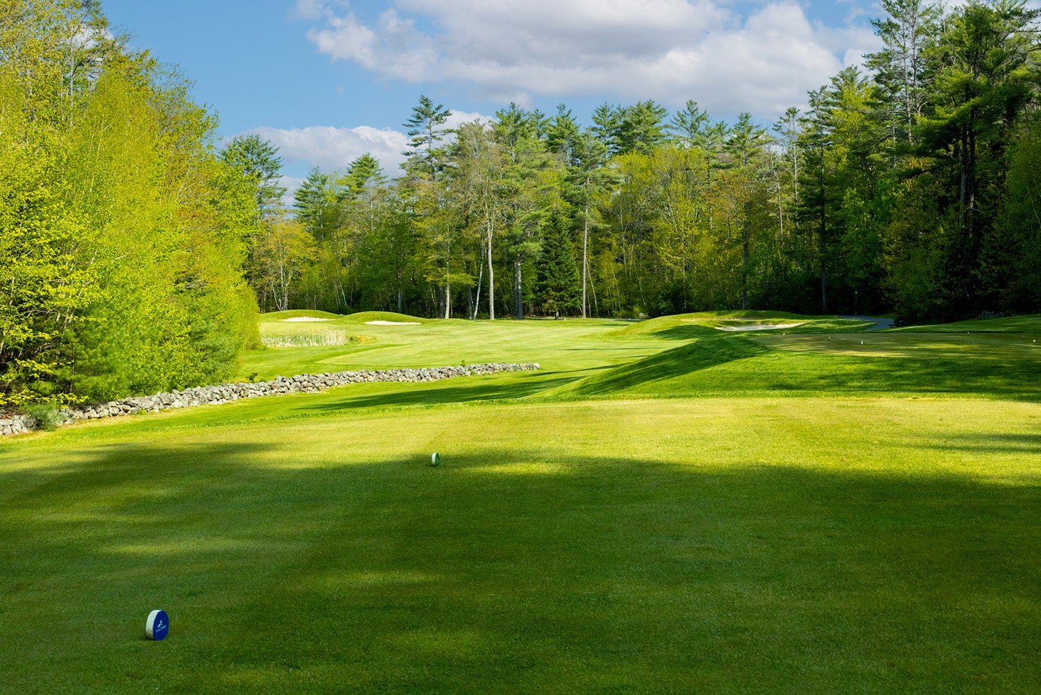 Golf hole from tee to green with stone wall