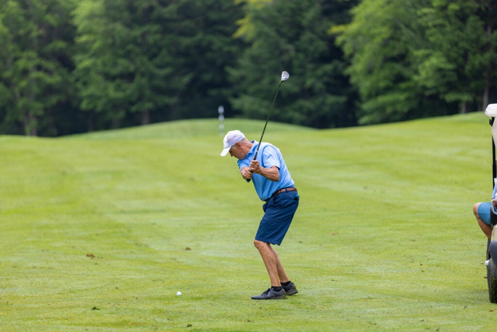 Older gentleman hitting golf ball in fairway