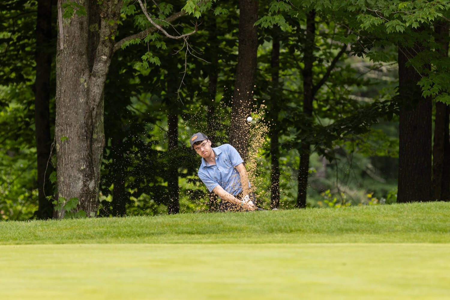 Man hits golf ball out of sand trap