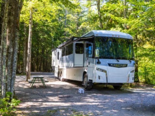 Exterior view of a Motorhome parked in forest RV site at Point Sebago Resort