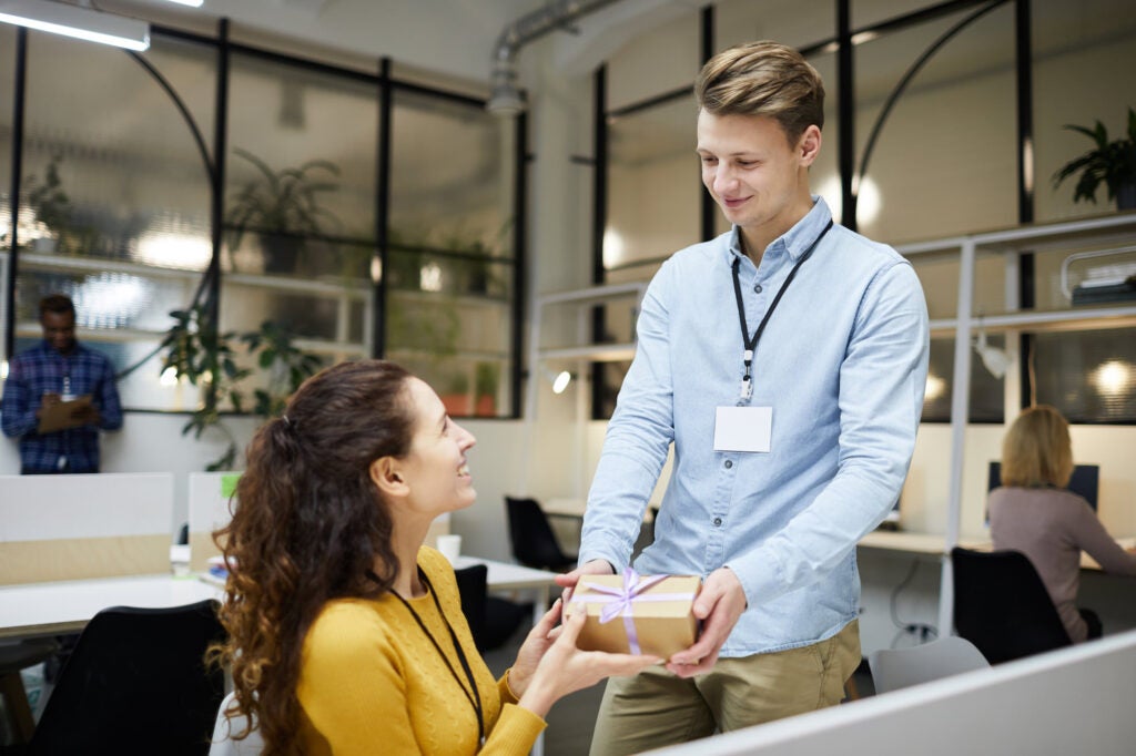 Happy lady accepting gift from colleague