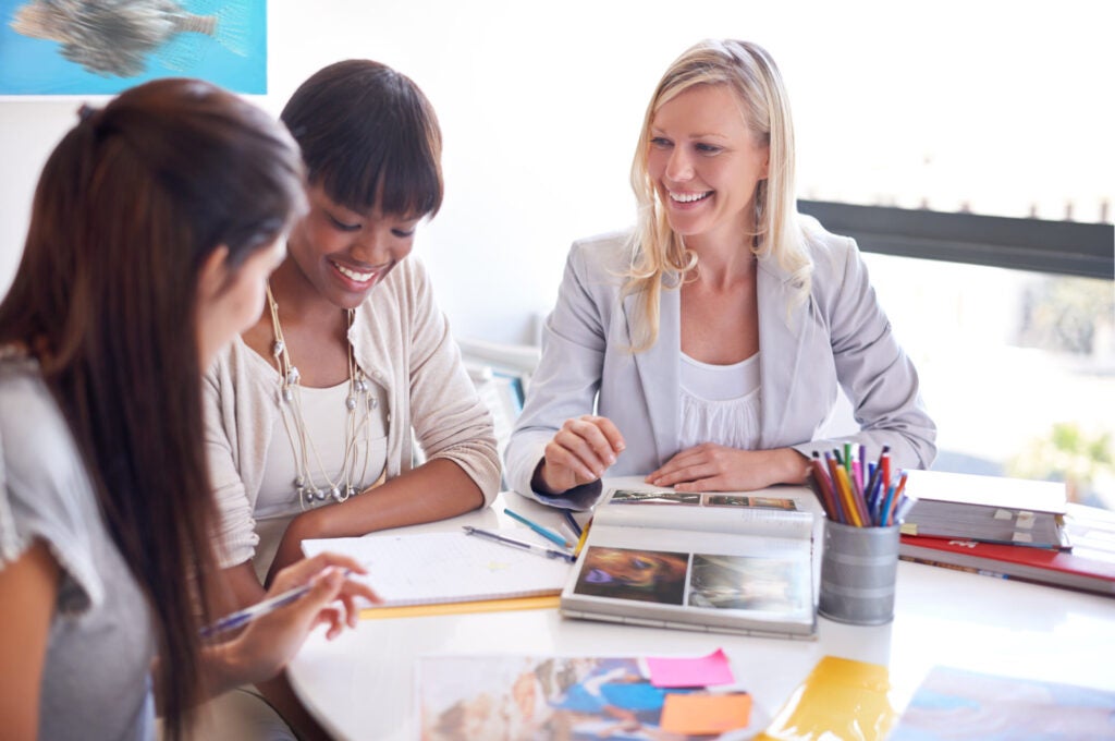 Cropped shot of three businesswoman gathered around a table in the office