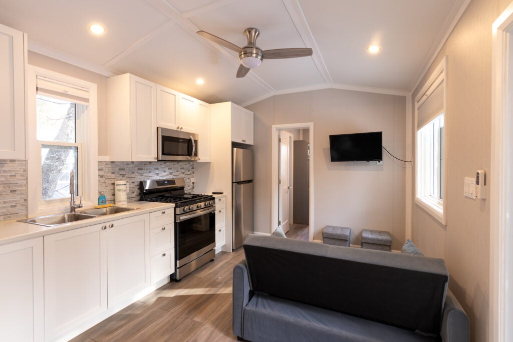 Kitchen with couch and television on the wall with door to second bedroom