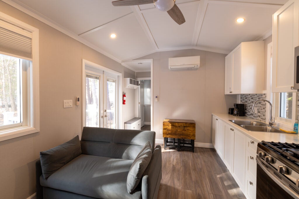 Kitchen with couch and folding table with door to master bedroom and exterior door.